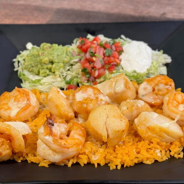 Mexican dish with shrimp and scallops over orange rice, served with guacamole, pico de gallo, and sour cream.