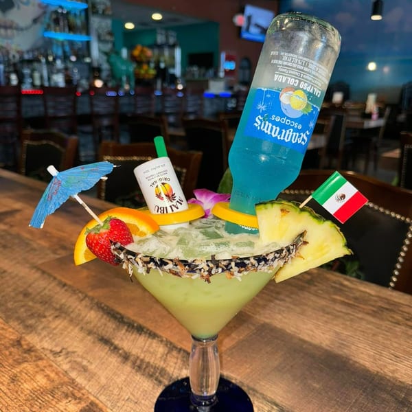 A La Plaza Fiesta margarita with a Seagram's bottle, Malibu, fruit, and a Mexican flag.